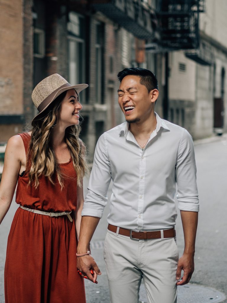 couple d'amoureux riant et heureux marchant ensemble dans les rues lors d'un shooting photo couple lifestyle
