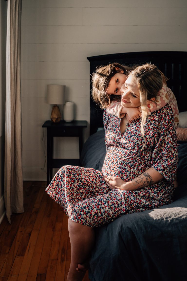 petite fille serrant dans ses bras sa maman enceinte lors d'un séance photo grossesse lifestyle à domicile à Marseille