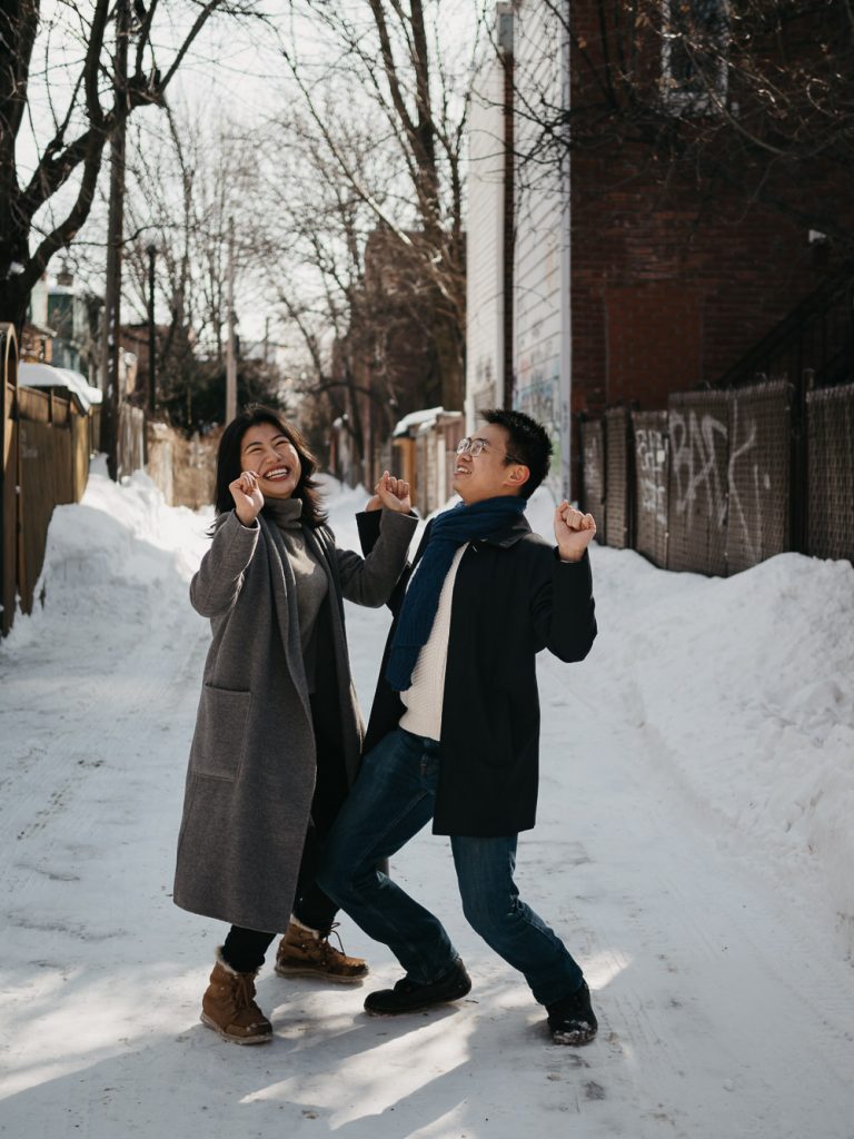 deux amoureux dansent dans une rue enneigée lors d'une séance photo de couple professionnelle en hiver
