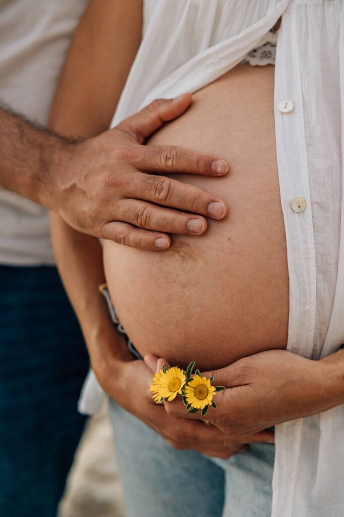 main du futur papa posée sur le ventre pendant une séance photo grossesse en couple