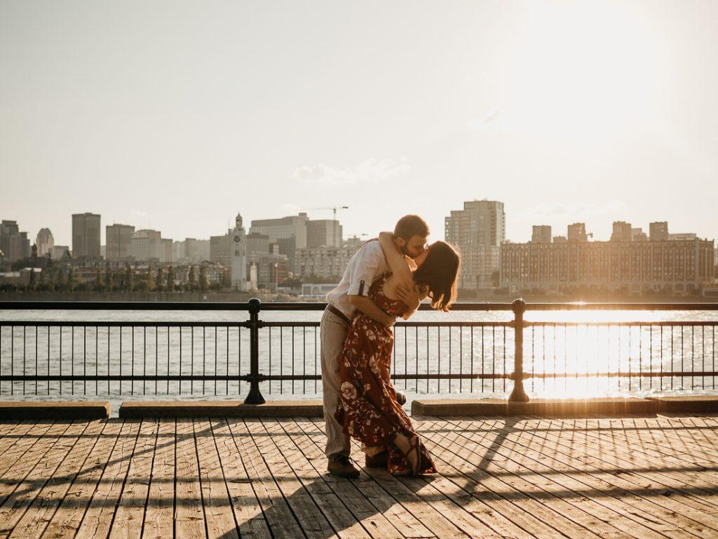 Couple d'amoureux qui s'enlace face au fleuve au coucher de soleil lors d'une séance photo de couple