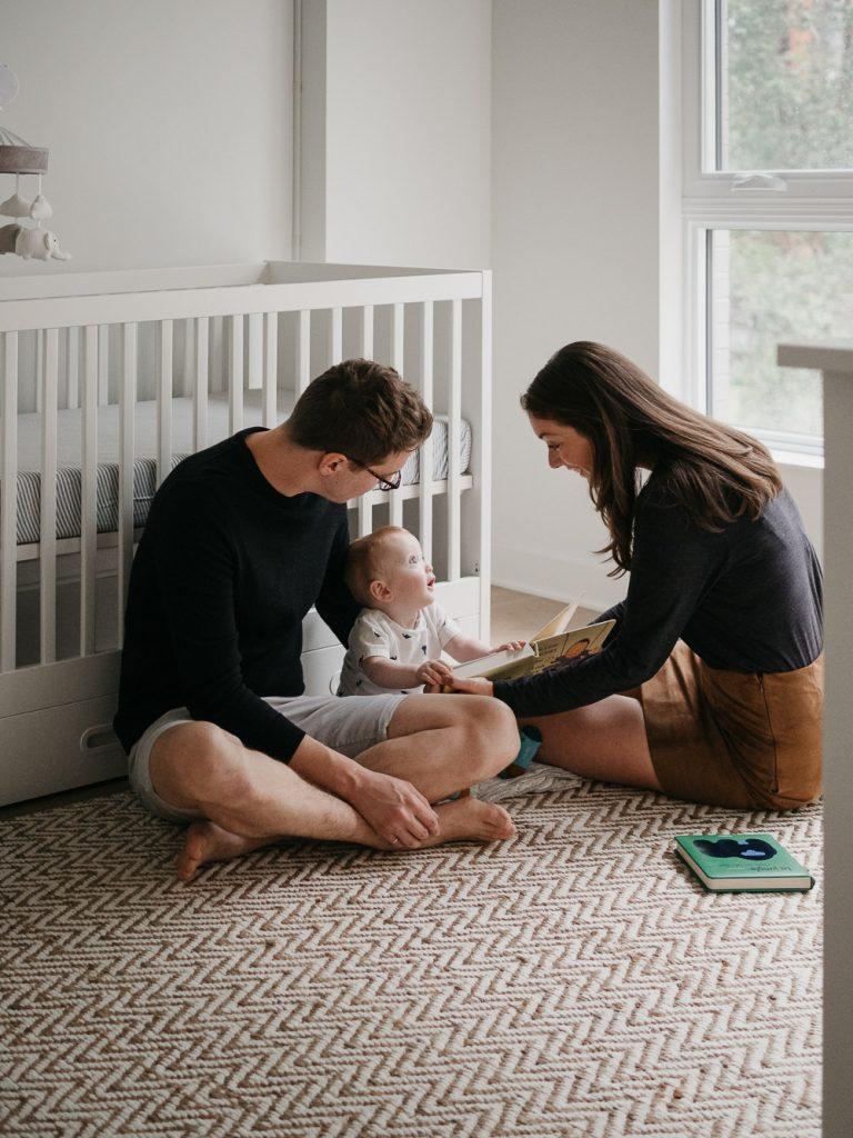 moment de la vie quotidienne de jeunes parents avec leur bébé lors d'un moment lecture dans la chambre de l'enfant pendant une session photo lifestyle à domicile à Marseille