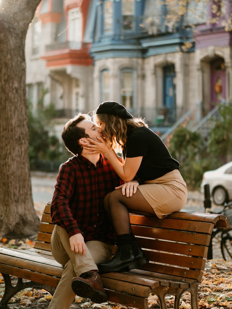 couple d'amoureux s'embrassent assis sur un banc lors d'un shooting photo de couple lifestyle dans un parc