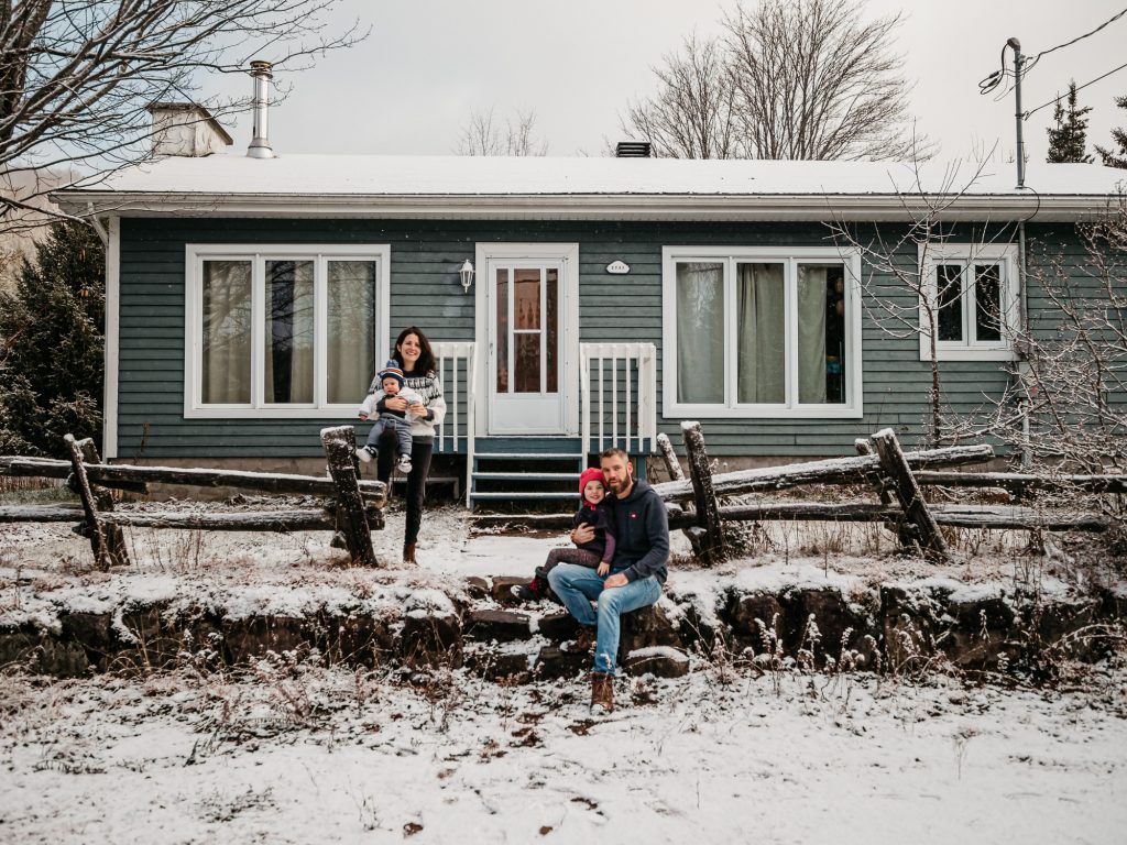 portrait de famille devant leur maison enneigée pendant une séance photo lifestyle