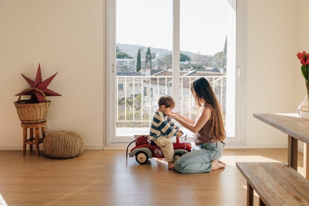 maman jouant avec son enfant près de la fenêtre pendant une séance photo grossesse à domicile à Marseille