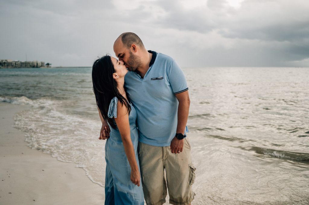 Un couple s'embrasse tendrement à la plage lors d'un shooting photo réalisé pendant leurs vacances à Marseille