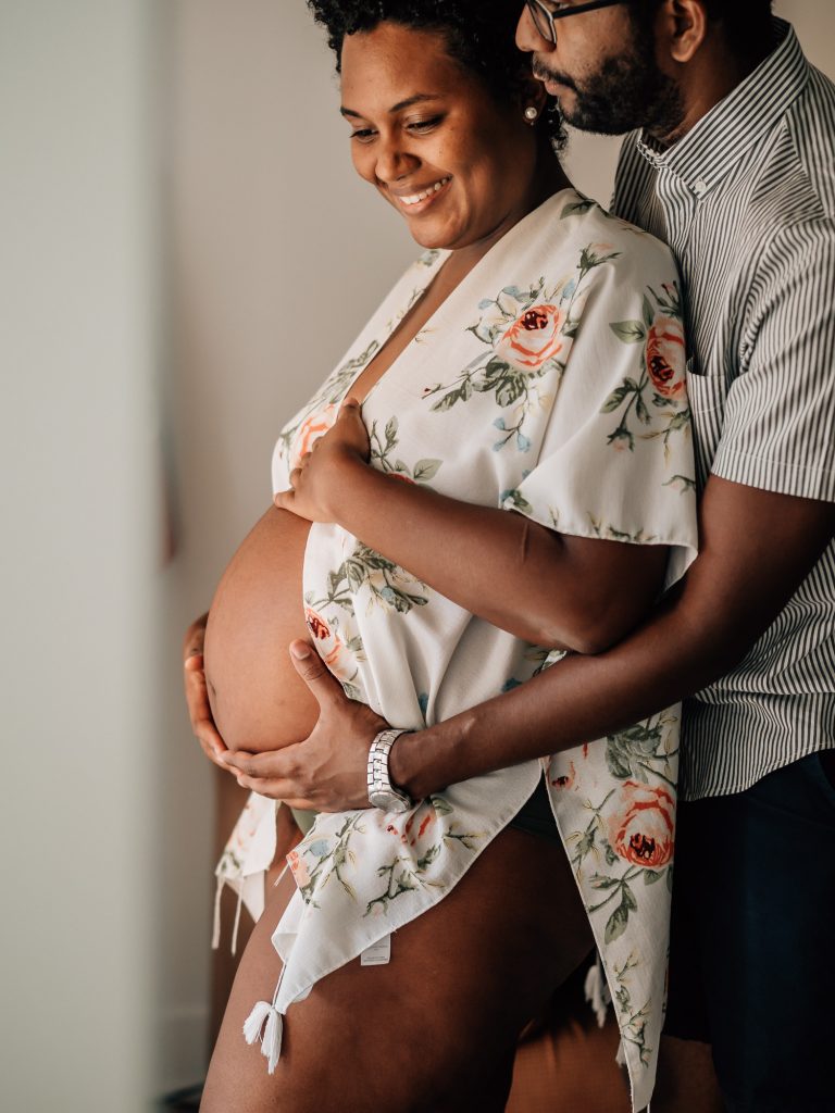 image extraite du portfolio de séance photo grossesse à domicile : future papa entourant le ventre rond de sa femme enceinte