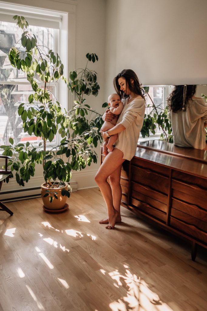 allaitement d'une maman et son bébé dans un rayon de lumière lors d'une séance photo peau à peau intimiste dans la chambre