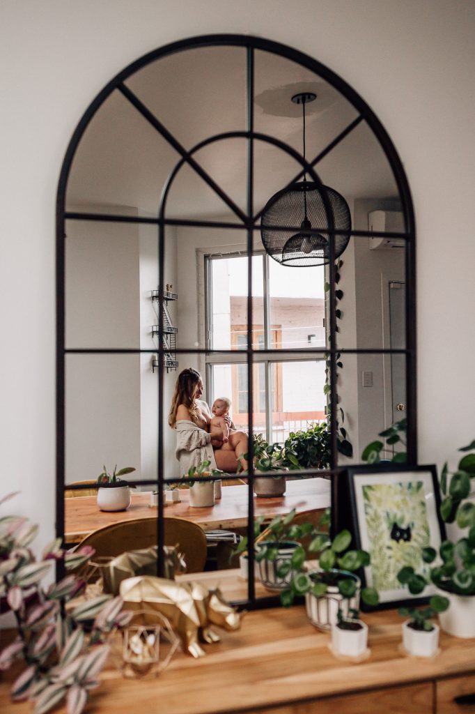 reflet dans un miroir d'une maman qui allaite son bébé nu dans un moment d'intimité, de tendresse et d'amour lors d'une séance photo peau à peau à domicile Marseille