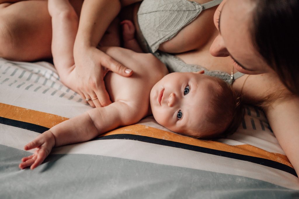 moment d'intimité, de tendresse et d'amour entre maman et bébé sur le lit lors d'une séance photo peau à peau et allaitement à Marseille
