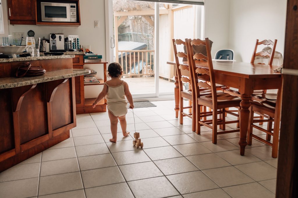 petit fille tire un jouet en bois dans la cuisine lors d'un shooting photo de vie quotidienne