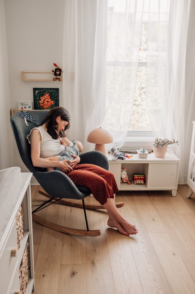 portfolio de séance photo de famille à domicile à Marseille : maman qui berce son nouveau-né dans la chaise berçante dans la chambre d'enfant