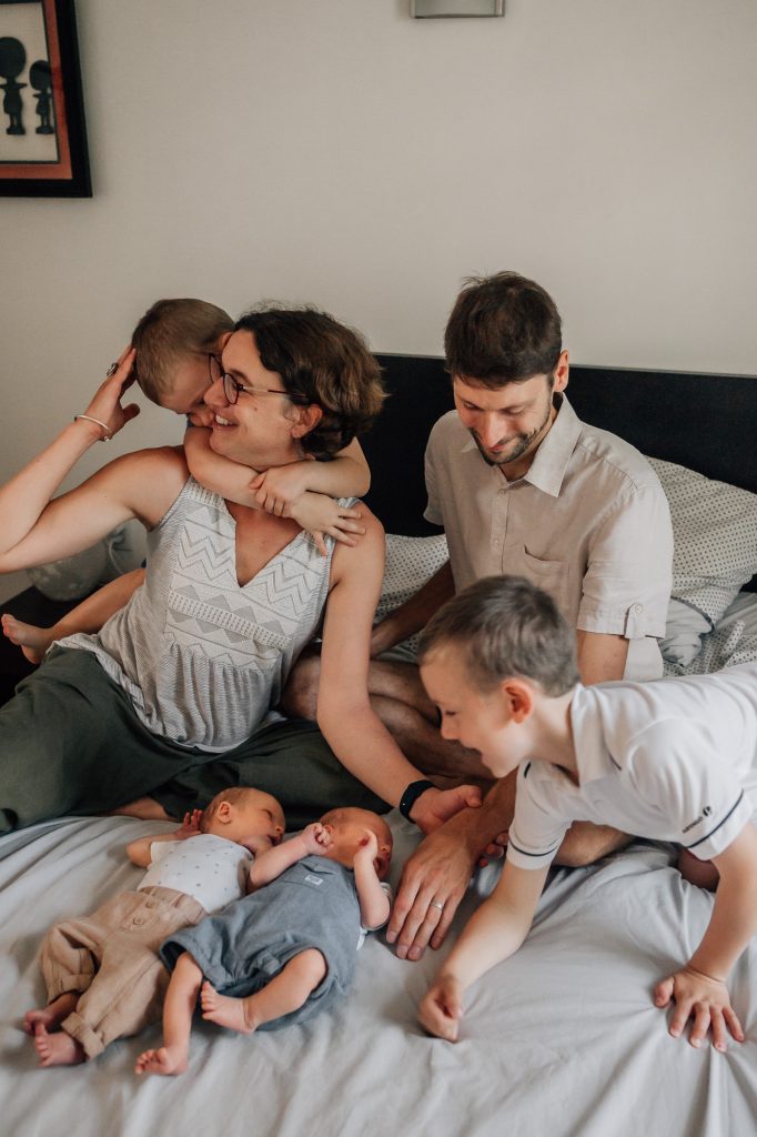 moment en famille sur le lit avec des bébés jumeaux, les deux grands frères et les parents lors d'une séance photo naturelle famille à la maison à Marseille