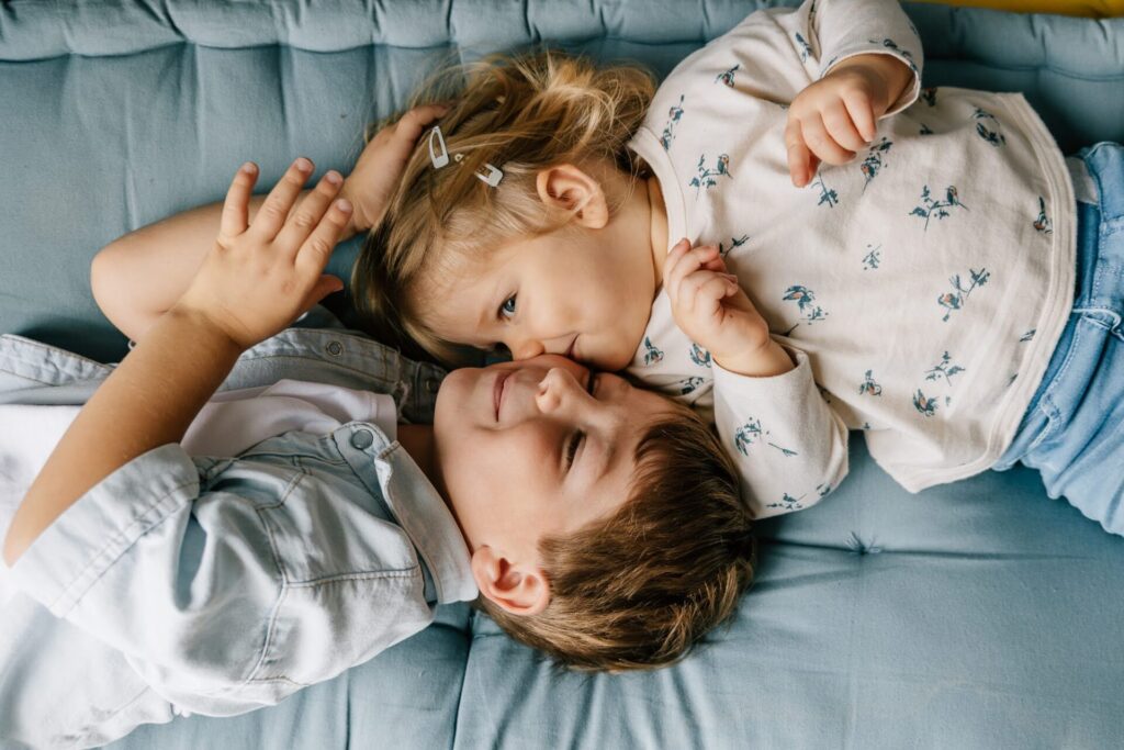Frère et sœur allongés sur un canapé lors d'une séance photo lifestyle à domicile