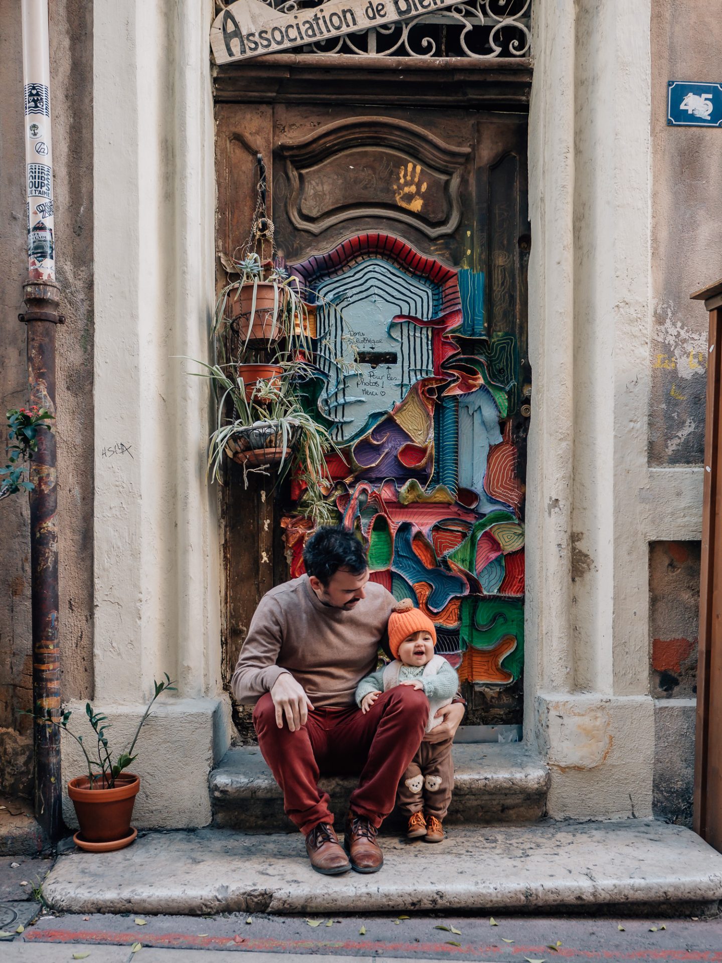 papa assis avec sa petite fille devant une porte colorée du quartier le Panier à Marseille lors d'un shooting photo famille