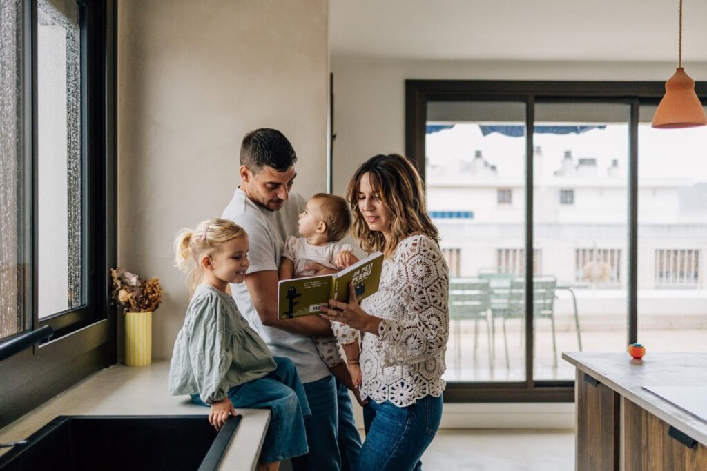 Parents et enfants lisant un livre dans la cuisine lors d'une séance photo de famille à domicile