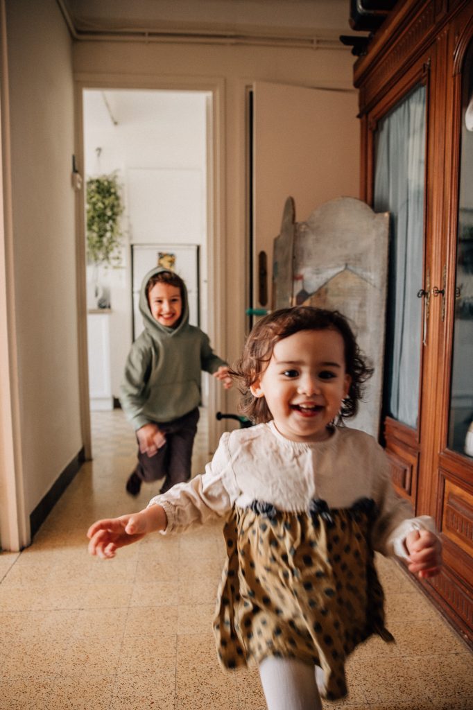frère et soeur courent dans l'appartement lors d'un reportage documentaire photo de famille à Marseille