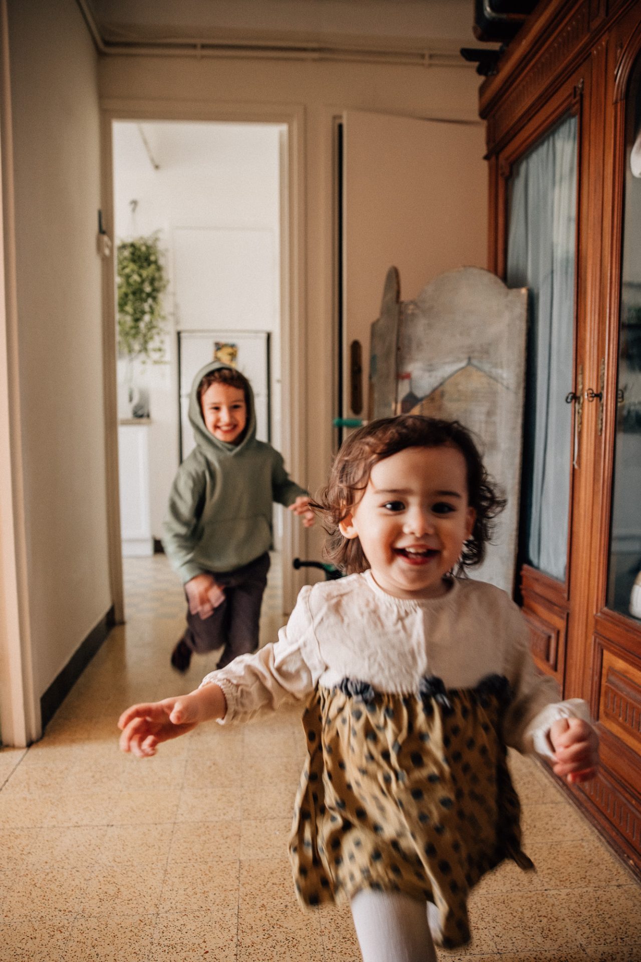 frère et soeur courent dans l'appartement lors d'un reportage documentaire photo de famille à Marseille