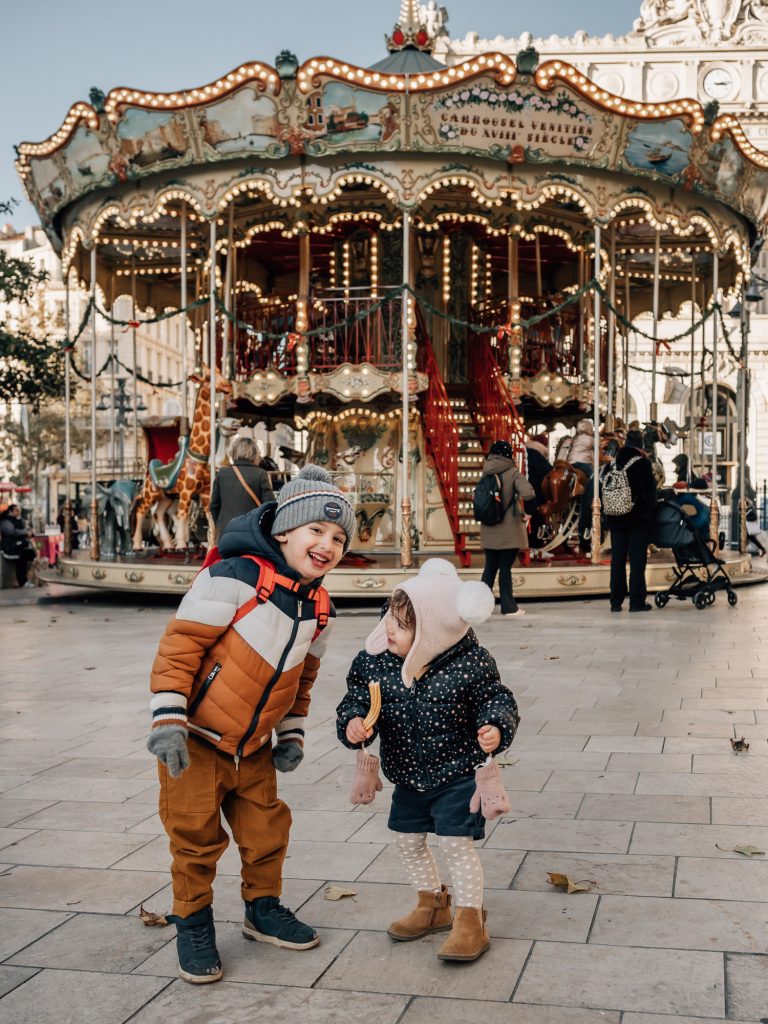 Un frère et une soeur heureux devant "La Belle Epoque Carrousel", le manège de la Canebière lors d'un shooting photo en hiver à Marseille