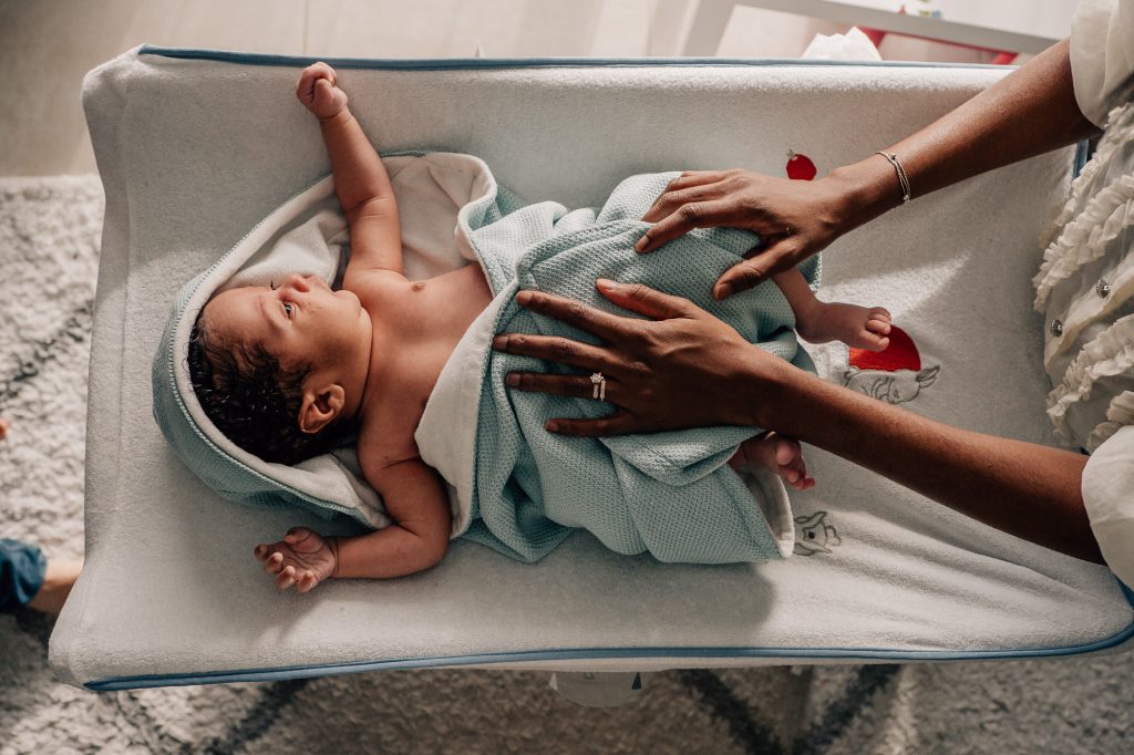 main de la maman qui sèche le bébé enveloppé dans une serviette sortant du bain lors d'une séance photo