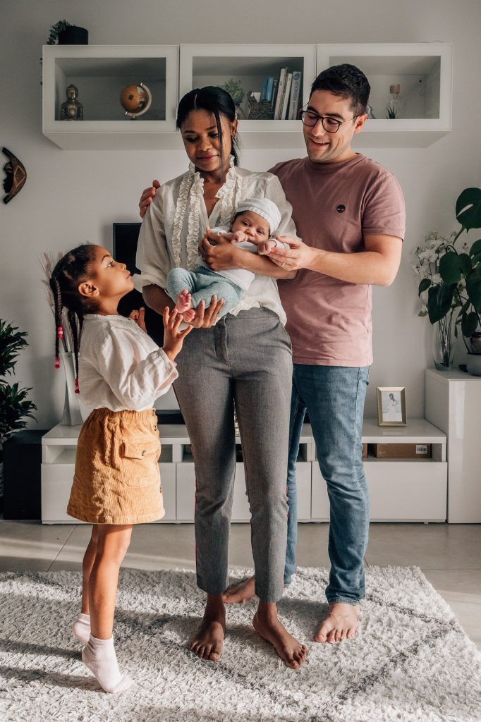 la famille réunie autour de bébé dans les bras de maman pour une photo de famille à la maison