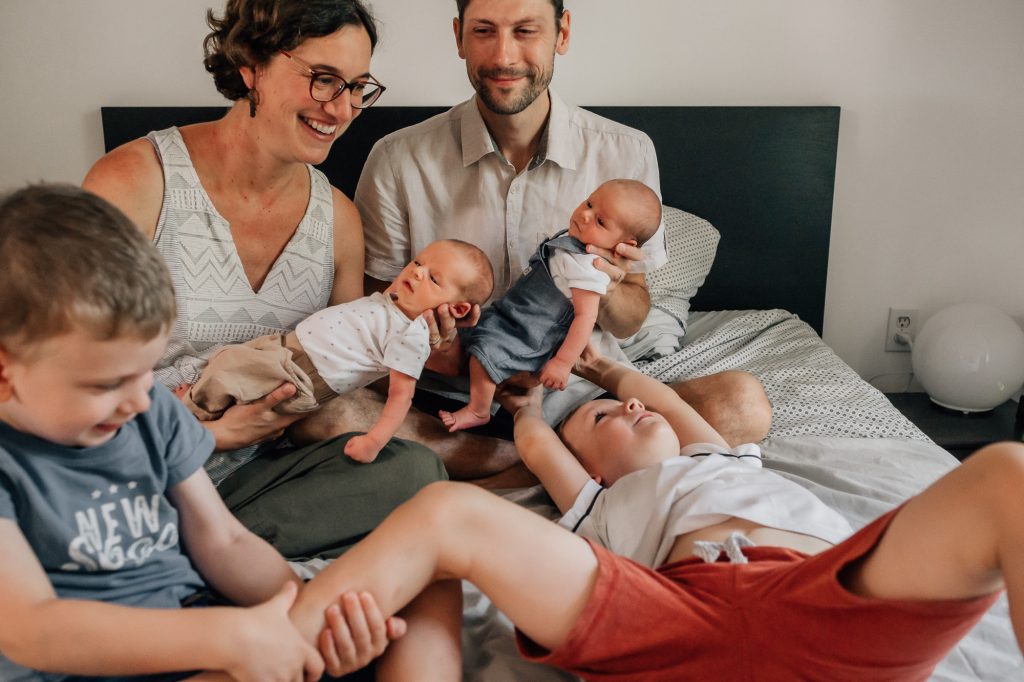 moment en famille sur le lit avec des bébés jumeaux, les deux grands frères et les parents lors d'une séance photo naturelle famille à la maison à Marseille