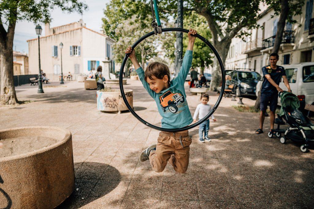 Enfants s'amusants sur les balançoires sur la place des Moulins dans le quartier du Panier à Marseille pendant une séance photo de famille