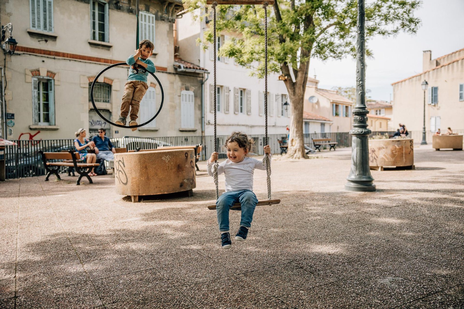 Enfants s'amusants sur les balançoires sur la place des Moulins dans le quartier du Panier à Marseille pendant une séance photo de famille