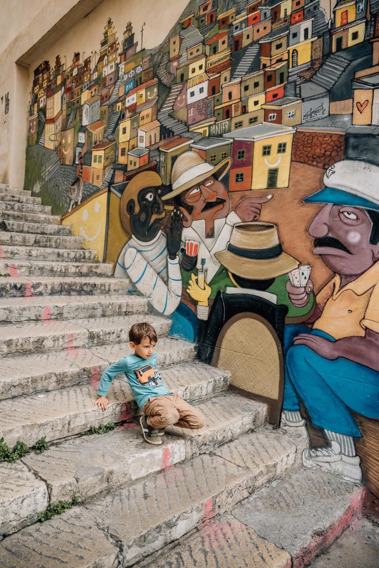 petit garçon assis dans les escaliers du Panier devant un mur de graffitis lors d'une séance photo famille à Marseille