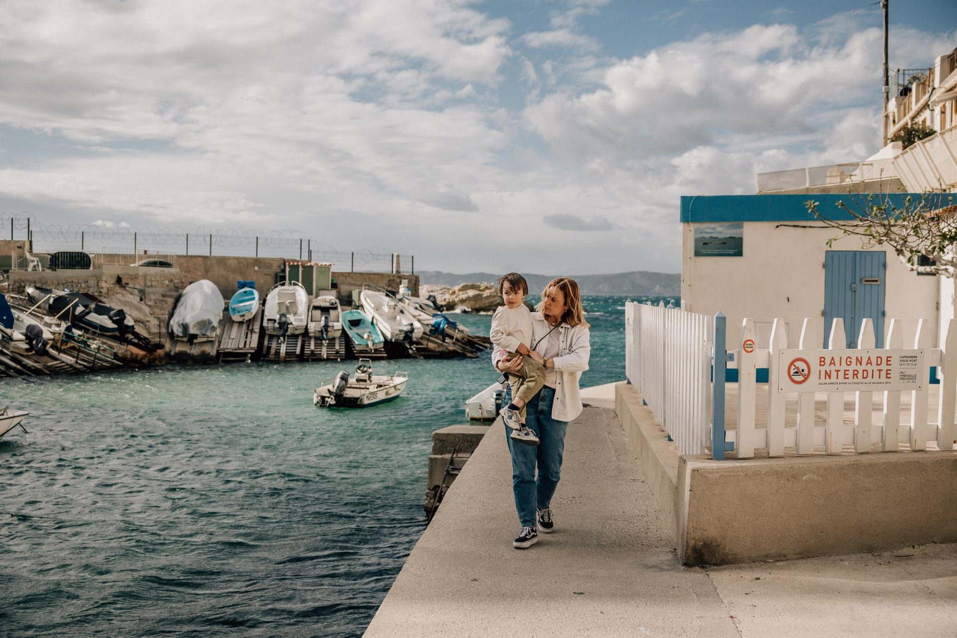 maman marche avec son petit garçon dans les bras au Port de Malmousque pendant une séance photo de famille à Marseille