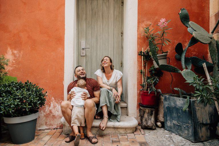 les parents et leur petit garçon sont heureux et rient lors d'une séance photo de famille dans les ruelles de Cassis