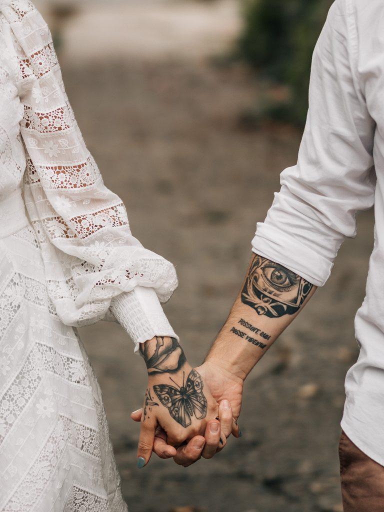 détail sur les mains d'un couple tatoué qui se tiennent les mains lors d'une séance photo engagement en ville à Marseille