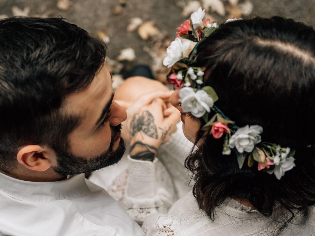 portrait serré d'un couple de jeunes mariés qui s'embrassent lors d'une séance photo de couple. Une couronne de fleurs est posée sur la tête de la jeune femme