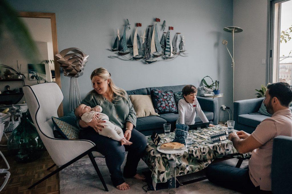 famille dans le salon en train de jouer à un jeu lors d'une séance photo bébé à domicile à Marseille