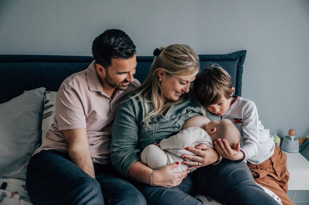 maman allaite son bébé avec sa famille autour d'elle lors d'une séance photo bébé à domicile à Marseille