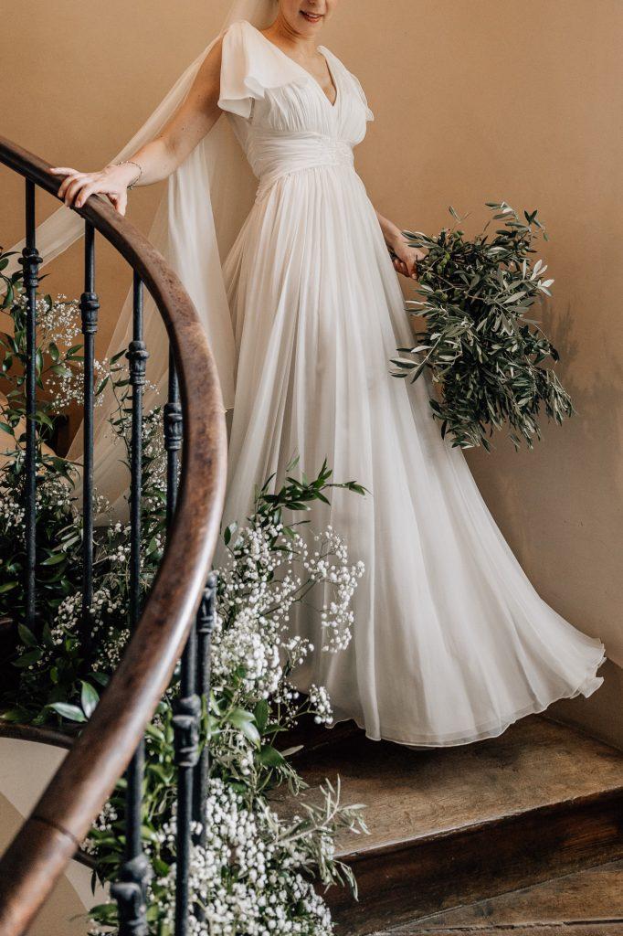 Mariée qui descend l'escalier fleuri lors de son mariage du Domaine du Vallon des Sources à l'Isle sur la Sorgue