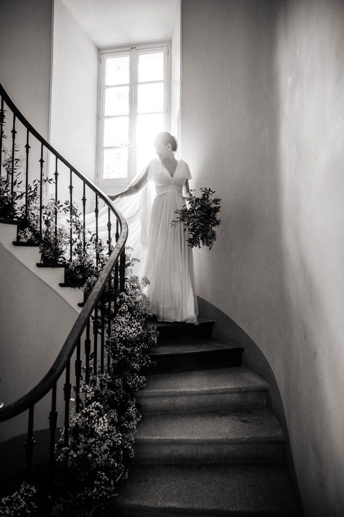 Mariée qui descend l'escalier fleuri lors de son mariage du Domaine du Vallon des Sources à l'Isle sur la Sorgue