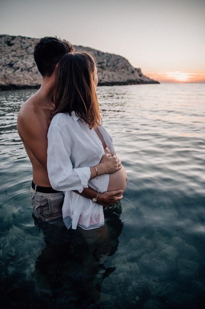 moment de tendresse d'un couple lors d'un shooting photo de grossesse dans l'eau des Calanques à Marseille