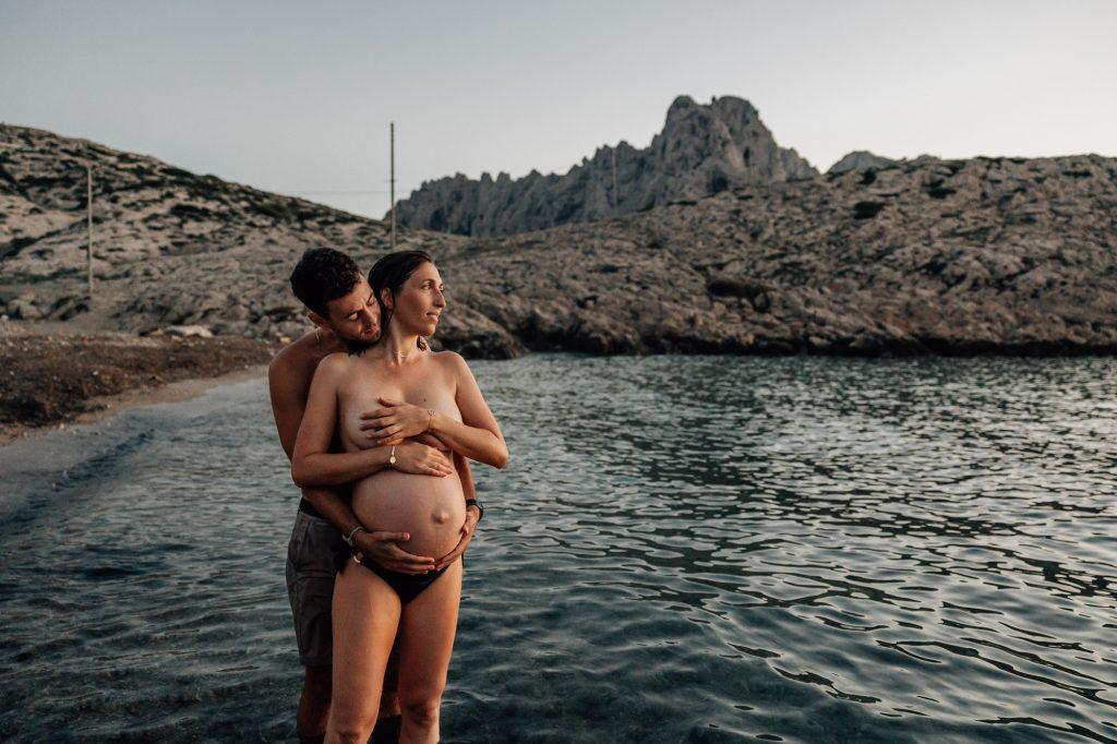 moment de tendresse d'un couple lors d'un shooting photo de grossesse dans l'eau des Calanques à Marseille
