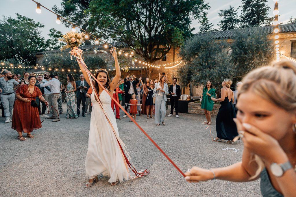 mariée joue au jeu du ruban avec son bouquet lors de son mariage en Provence couvert par une photographe professionnelle