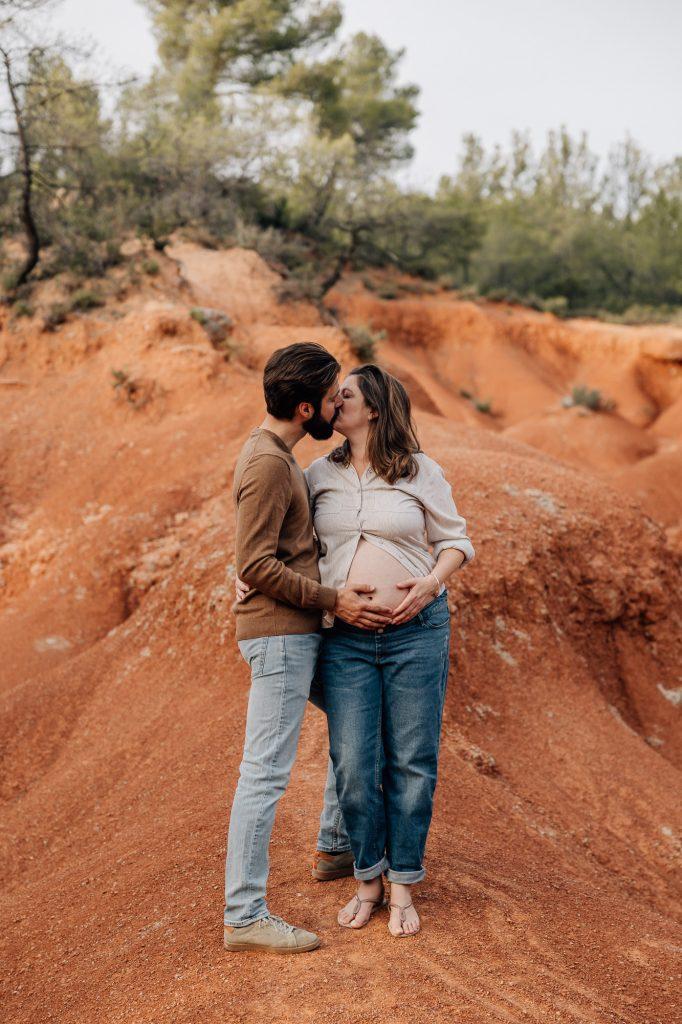 couple s'embrassant et caresse le ventre de la future maman lors d'un shooting grossesse aux terres rouges à la sainte victoire près d'Aix-en-Provence
