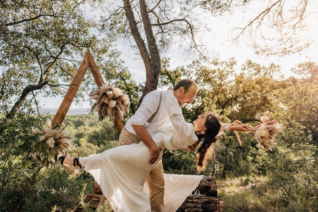 Le marié renverse la mariée dans ses bras devant le superbe décor moderne et végétal après la cérémonie laïque dans la forêt près d'Aix-en-Provence