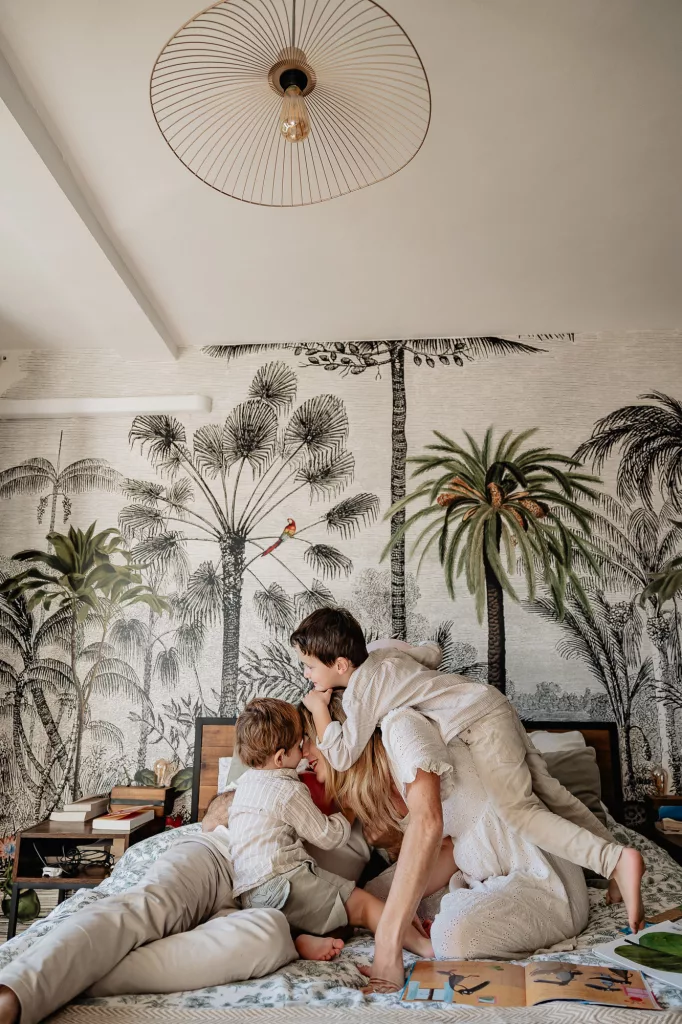 Enfants et parents jouent sur le lit des parents lors d'un shooting photo lifestyle de famille à domicile dans Marseille 13007
