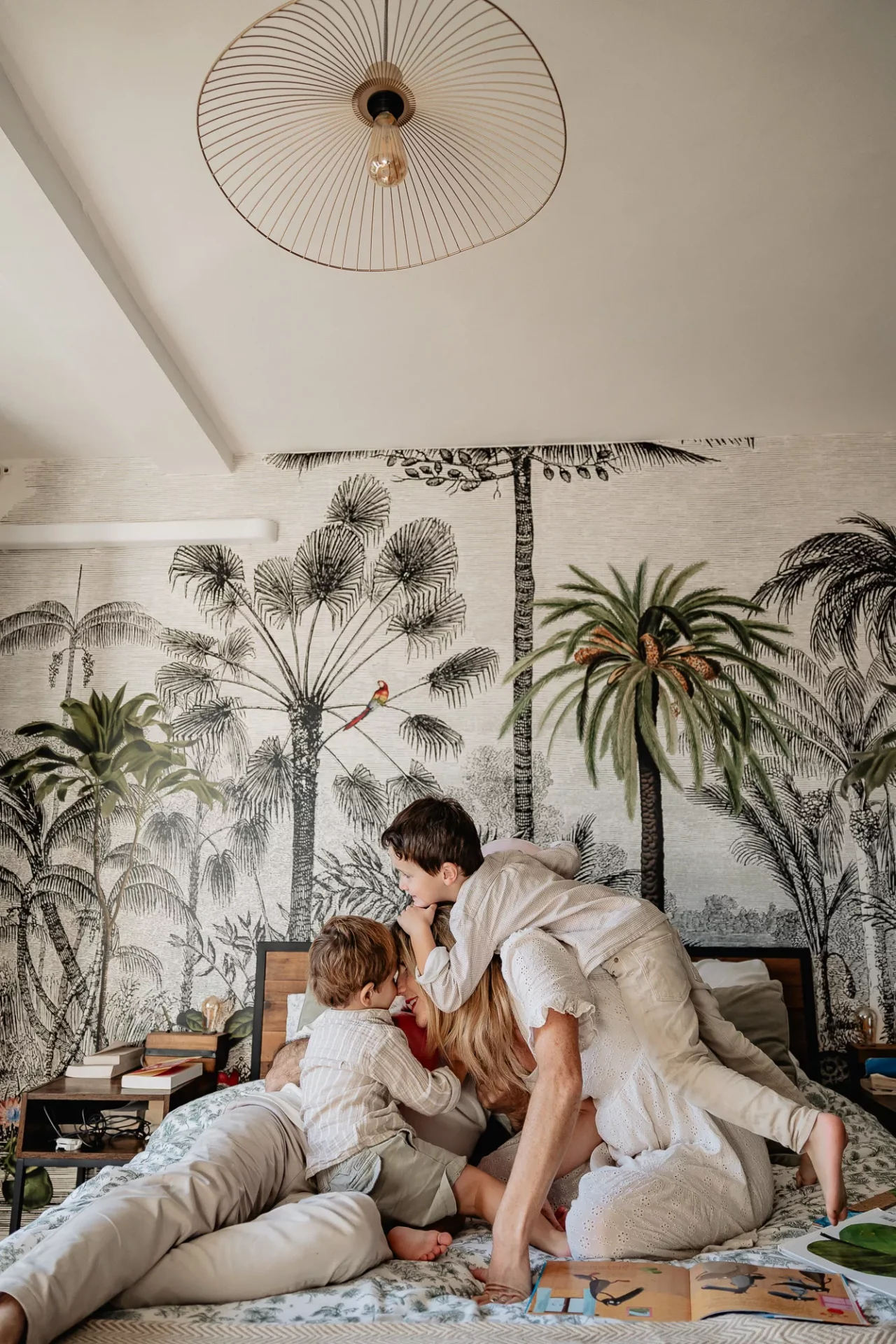 Enfants et parents jouent sur le lit des parents lors d'un shooting photo lifestyle de famille à domicile dans Marseille 13007