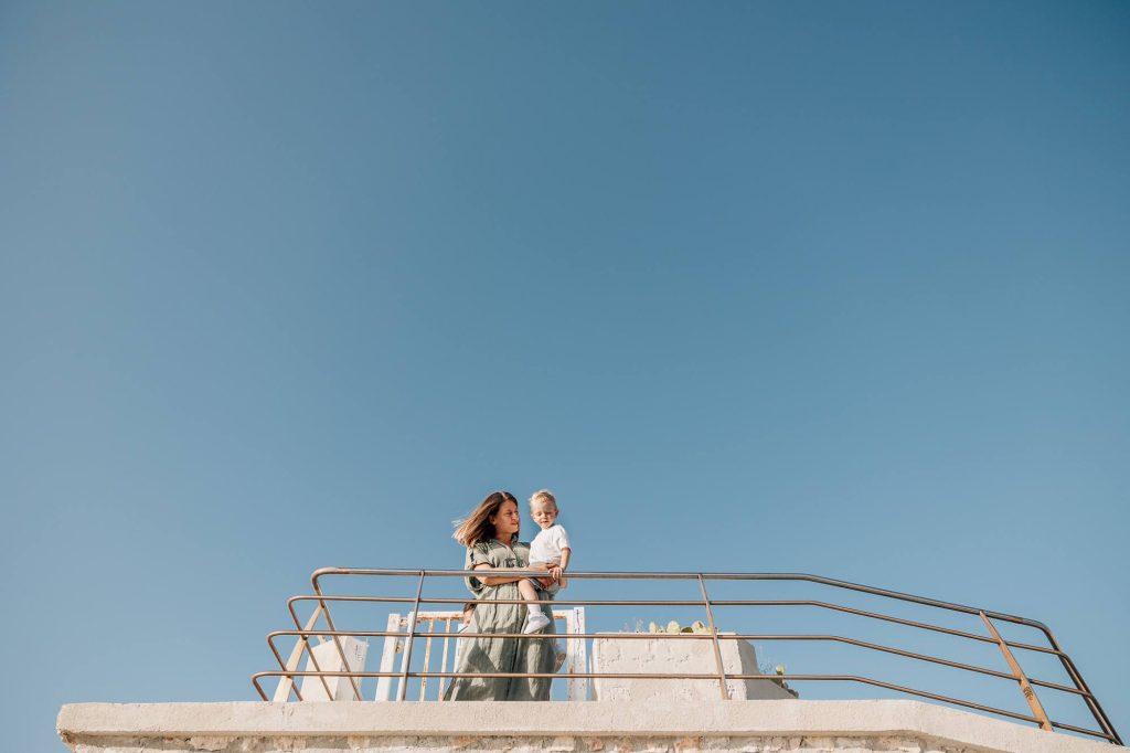 Maman tient son fils dans les bras devant un grand ciel bleu de Marseille lors d'une séance photo de famille