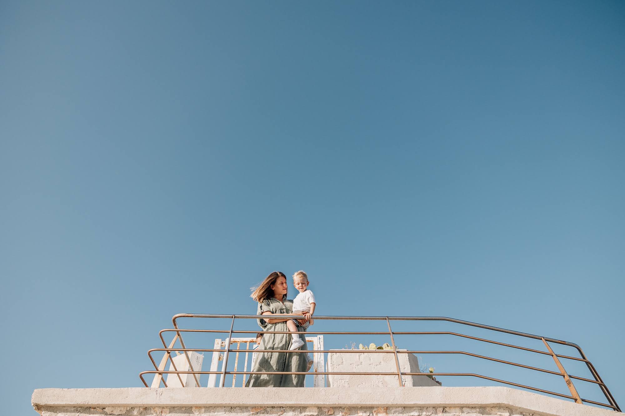 Maman tient son fils dans les bras devant un grand ciel bleu de Marseille lors d'une séance photo de famille