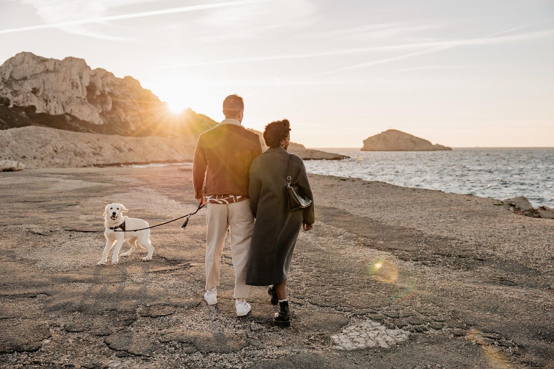 couple se promène avec son chien au coucher de soleil aux Goudes lors d'une séance photo à Marseille