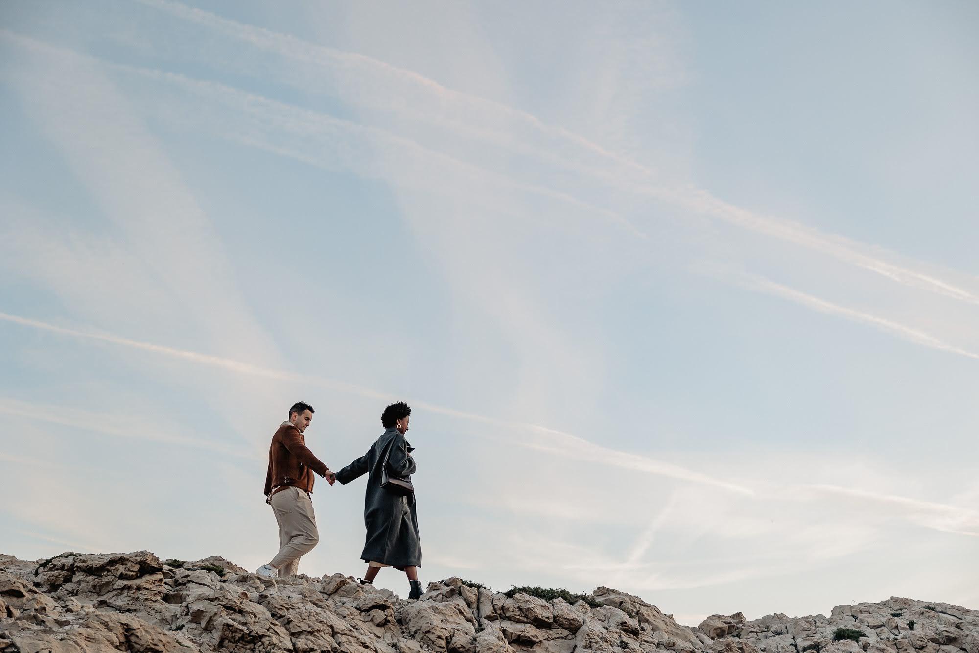 couple qui marche en se tenant la main dans les Calanques de marseille lors d'un shooting photo aux Goudes à Marseille