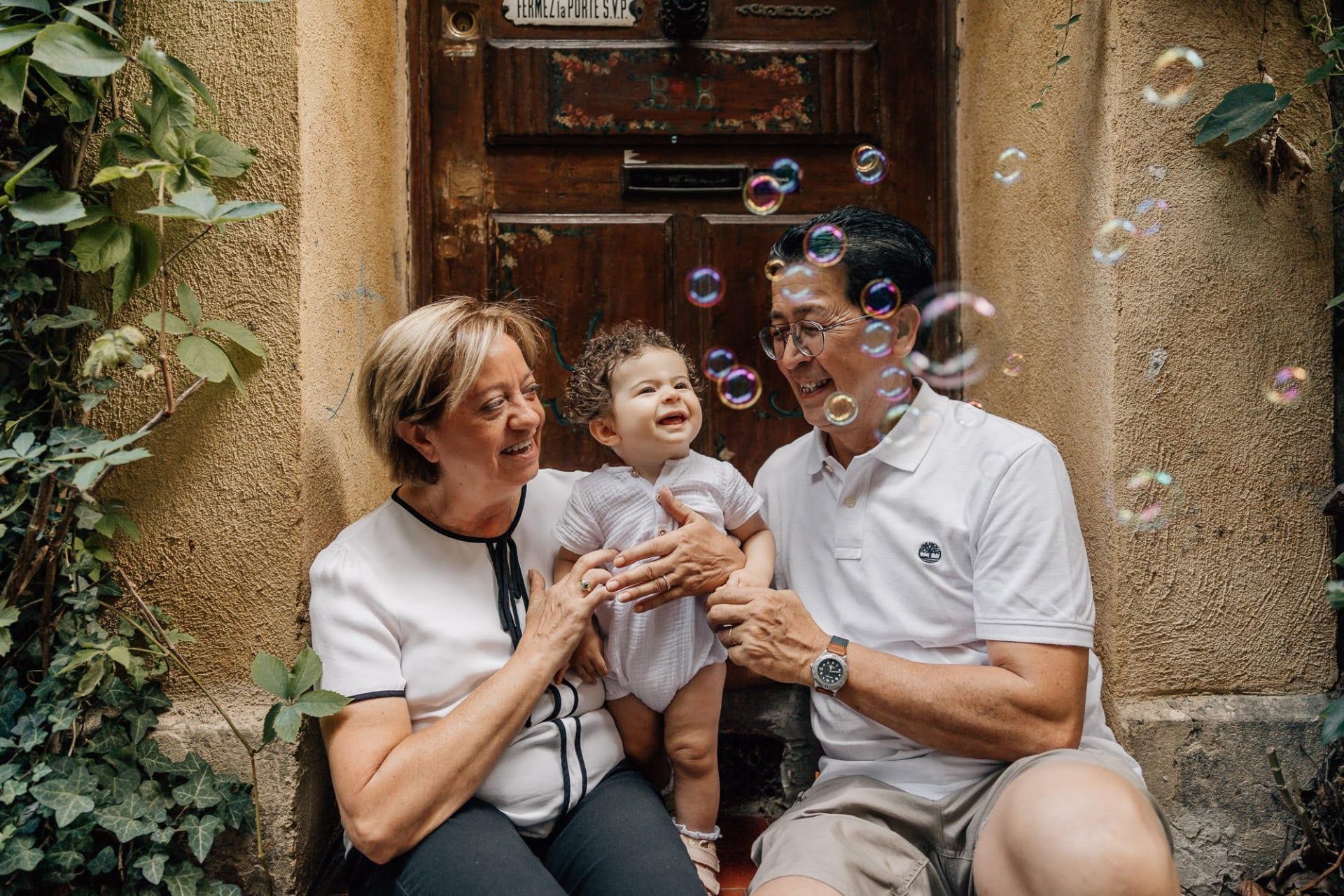 grands-parents qui s'amusent avec leur petite fille à faire des bulles lors d'un shooting photo famille au Panier à Marseille