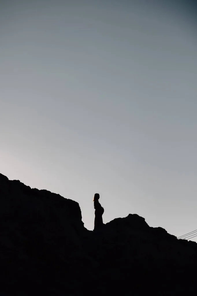 Silhouette de femme enceinte debout sur les rochers des calanques à Marseille au coucher du soleil